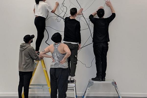 students at a white wall creating artistic shapes