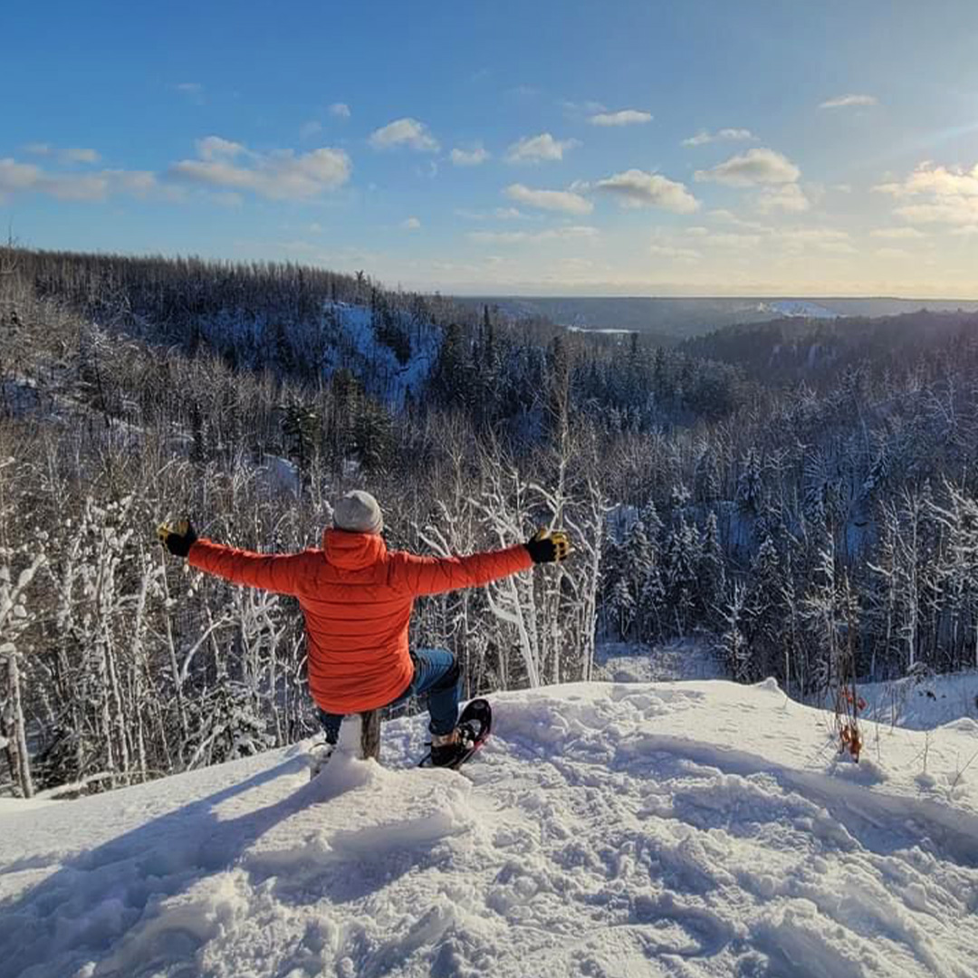 Student admiring the view from the top of a snowy mountain whilst wearing skis