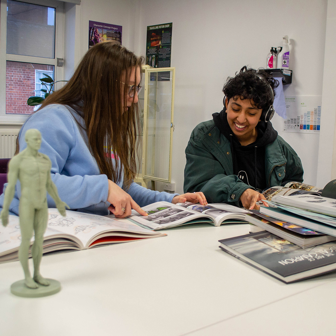 Two students studying books about game art