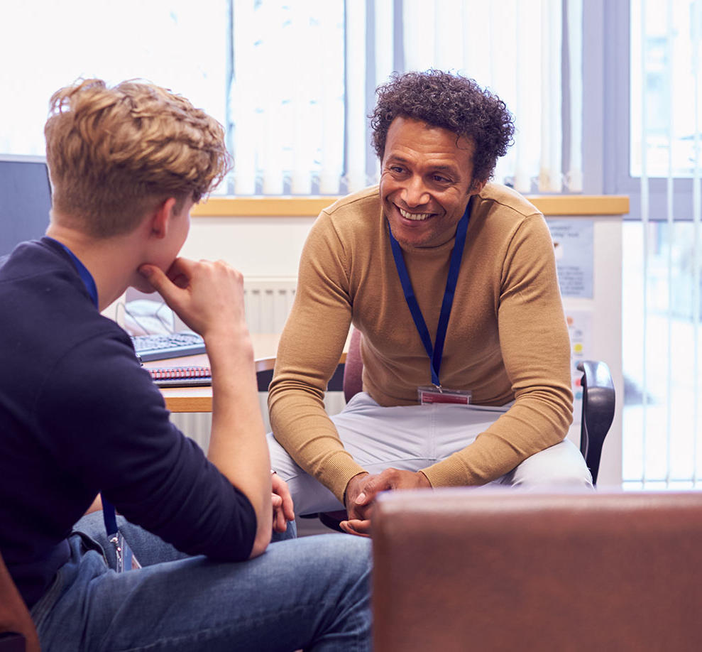 A smiling male counsellor is speaking to a student