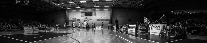 Black and white image of people playing indoor basketball
