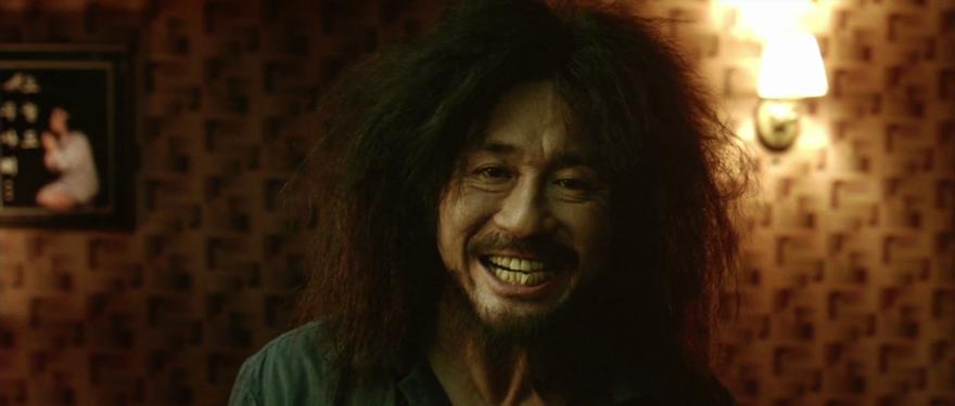 A still from the film Oldboy of a man with extremely backcombed hair grimacing