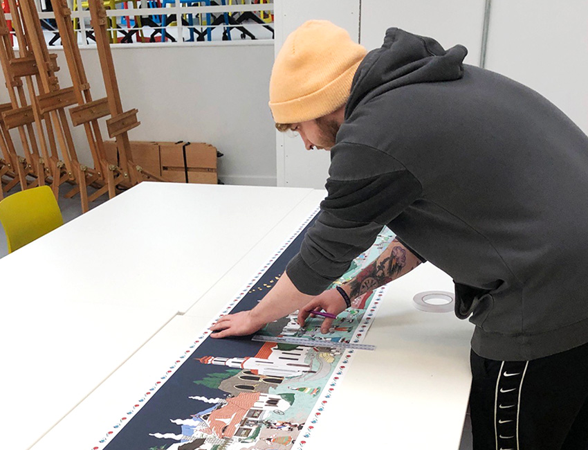 A student working on a large illustration of a medieval landscape