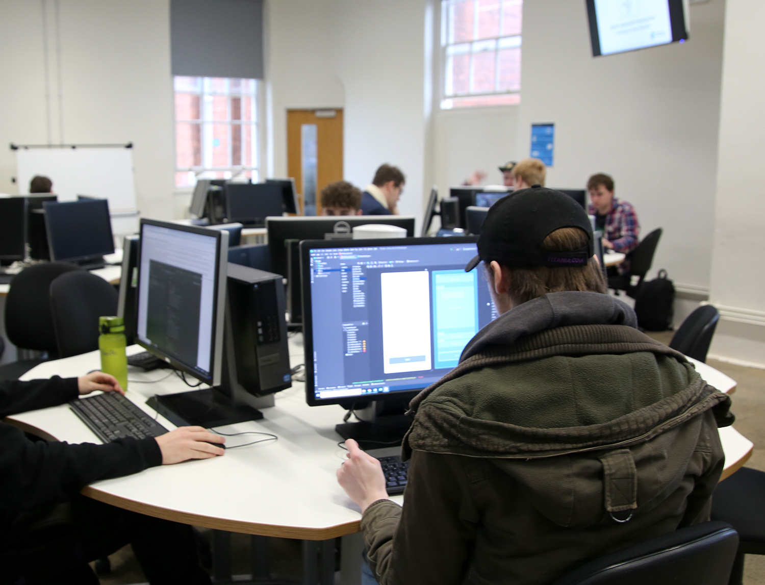 Student coding in class with other students in the background