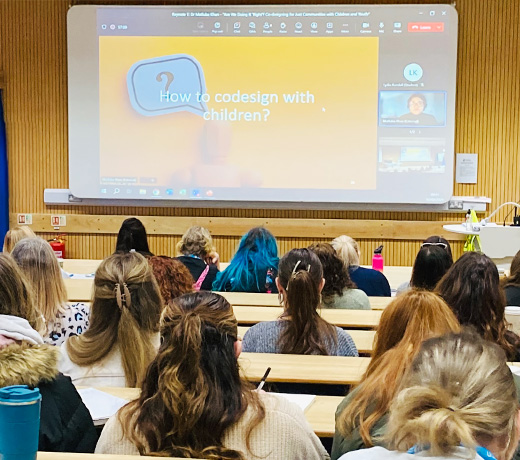 A lecture theatre full of students during a talk on 'codesigning with students'