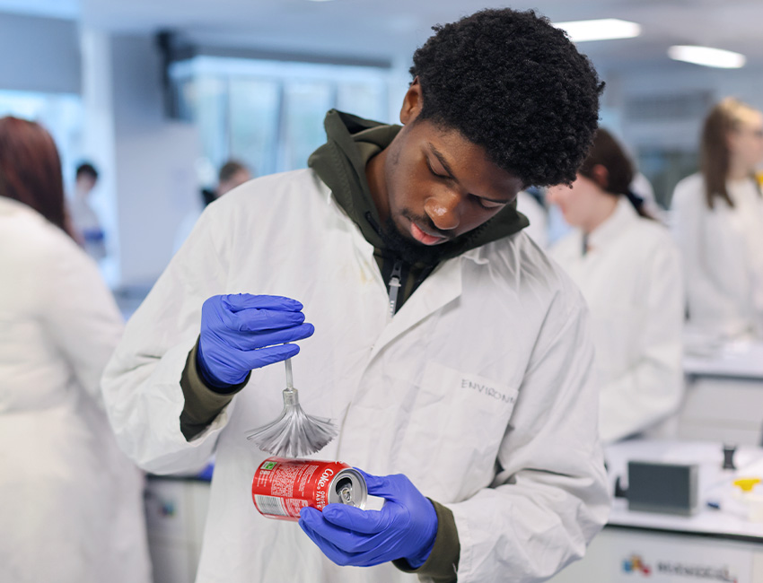 A Forensic Science student dusting a Coca Cola can for fingerprints in a laboratory