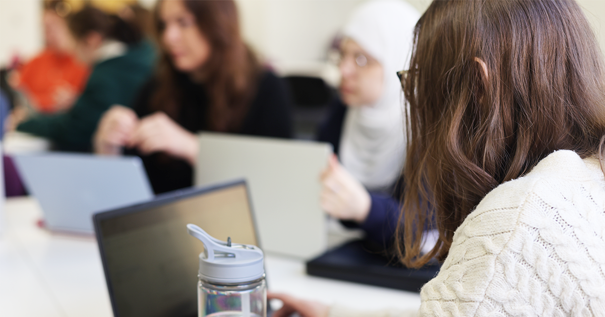 Student at a desk in a classroom with laptop open