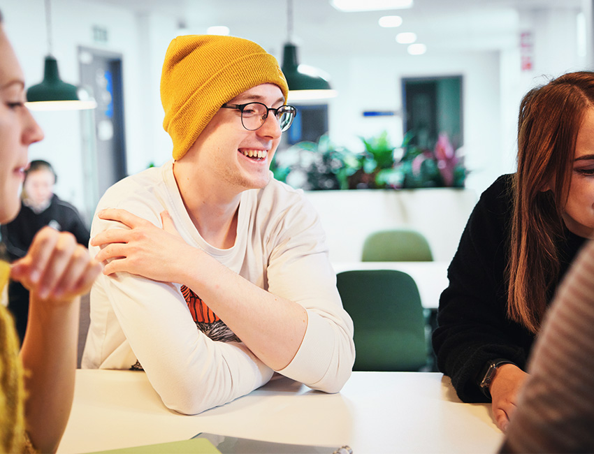 Student smiling whilst working with a group of other students