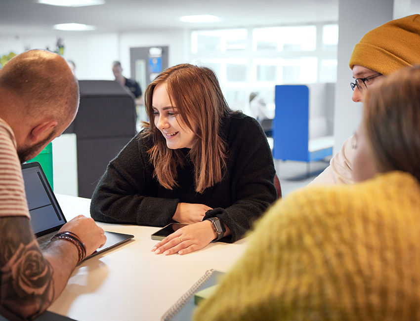 Four students gathered around a laptop