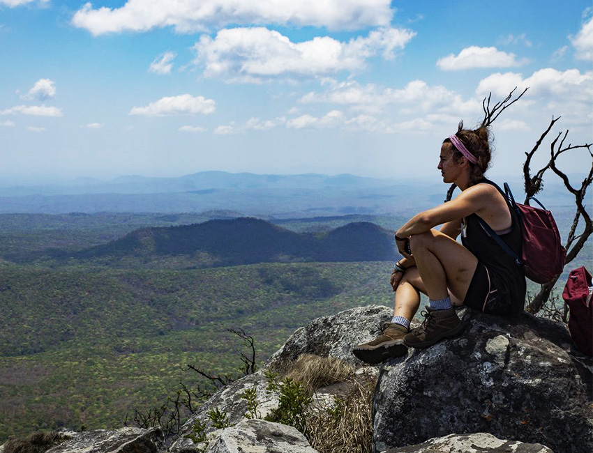 A girl sat on a rock, looking at a view