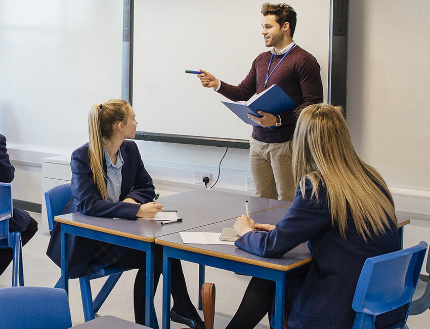 A student teacher is working with a group of older children in a classroom