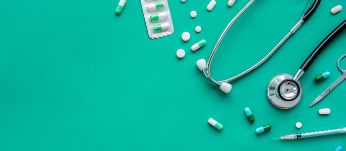 Pills and medical equipment on green background