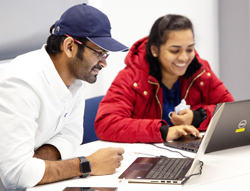 Two business students working together on laptops