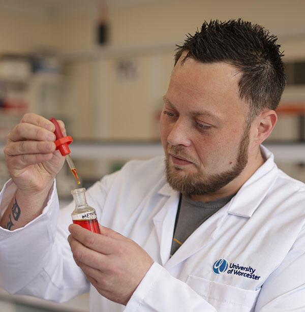 A student is holding a pipette full of red liquid