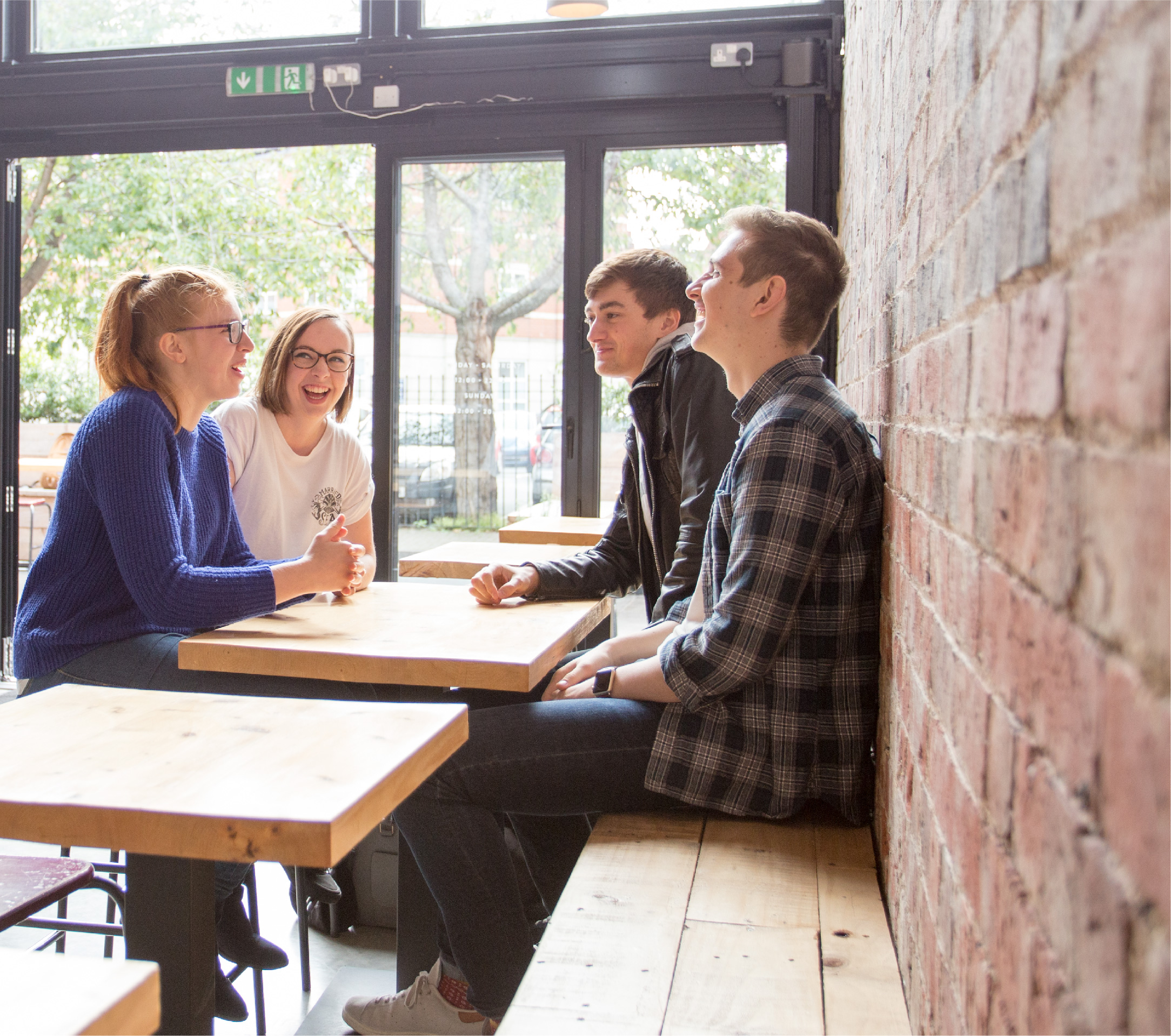 Four students laughing around a table in a restaurant