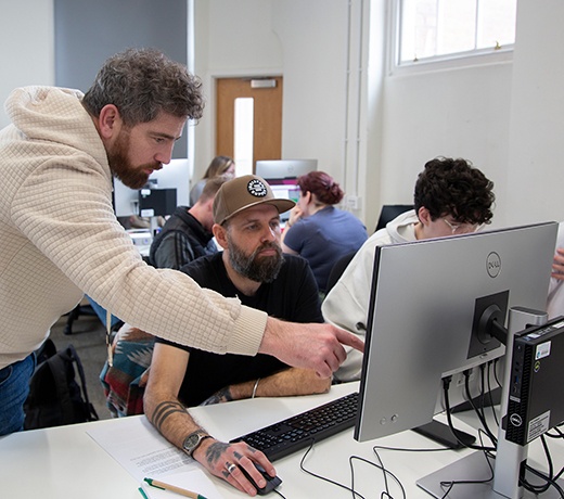 A lecturer supporting a student with a computer task