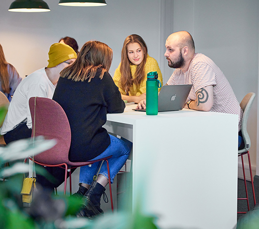 A group of students talking and looking at a computer