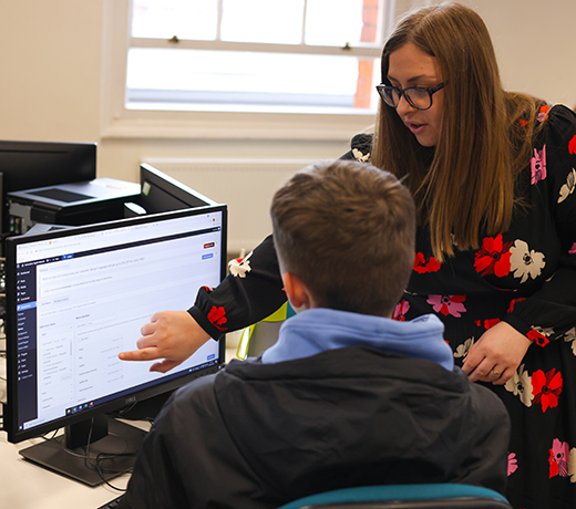 A lecturer supporting a student with a computer task