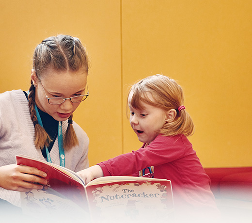 A student reading a picture book with a young child