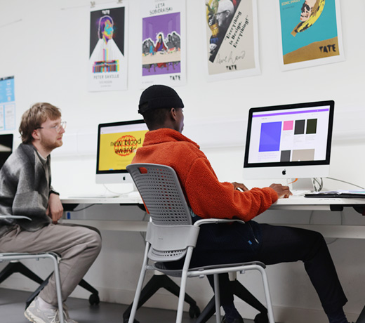 Two graphic design students working on Mac computers