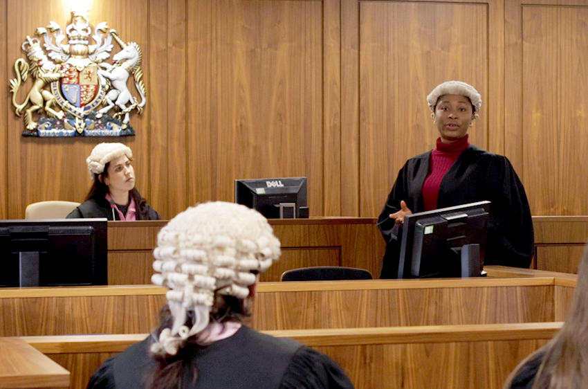 Law students during a mock court trial, with one student stood and addressing the room