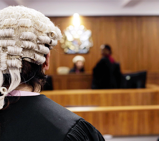 A law student wearing a wig and looking out at a mock court trial