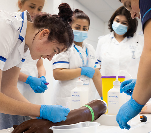 A group of midwifery students practicing with a cannulation model