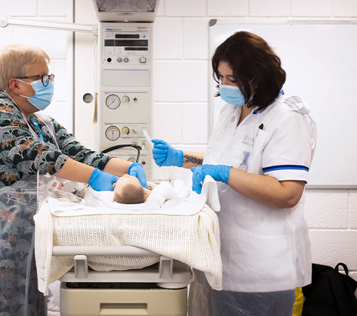 A Midwifery student and lecturer practicing skills with a baby manakin