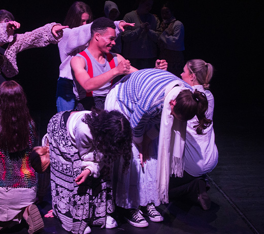 A large group of Musical Theatre students huddled together as part of a performance