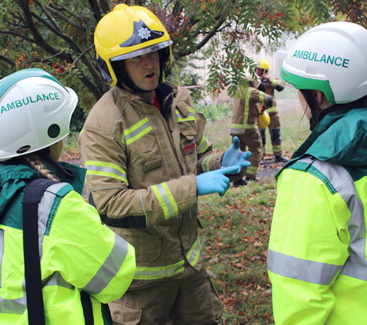 Two paramedic students talking to a firefighter