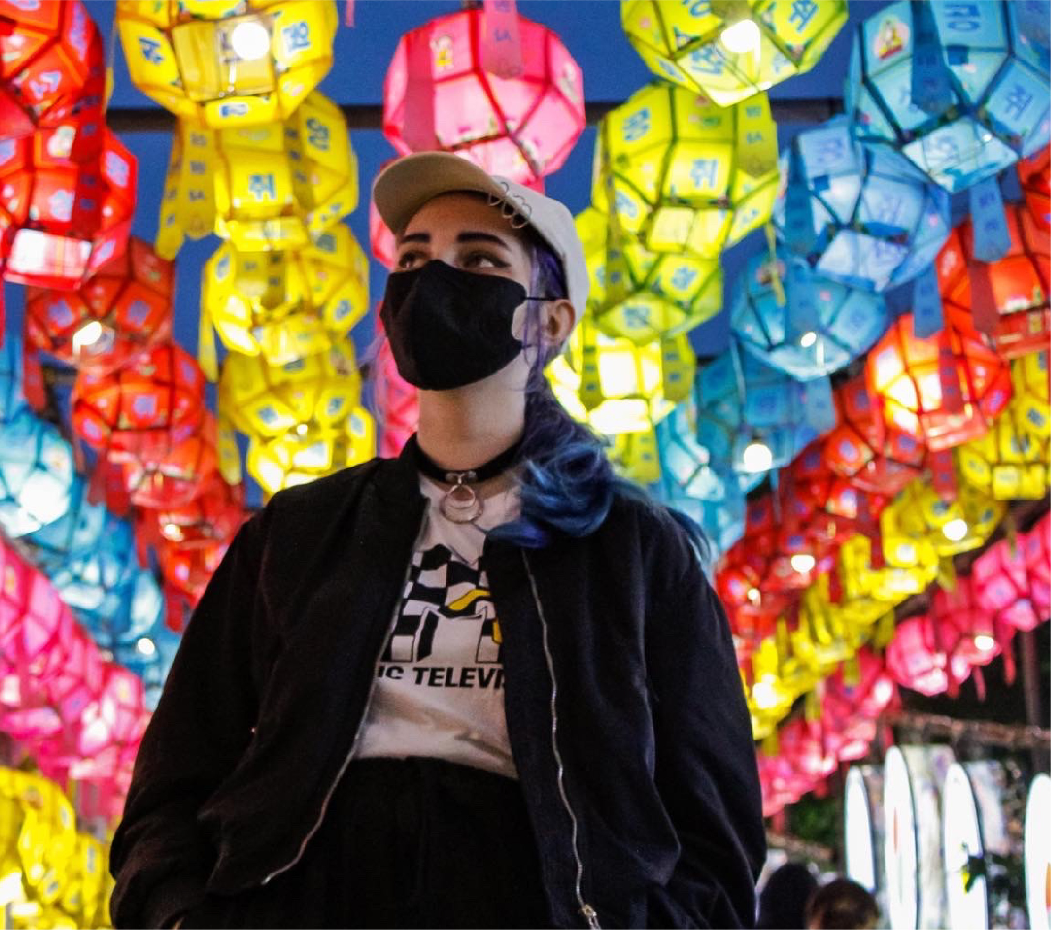 A student wearing a face mask with colourful lanterns behind her