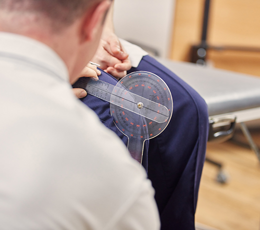 Physiotherapy student using a goniometer to measure the angle of someone's knee