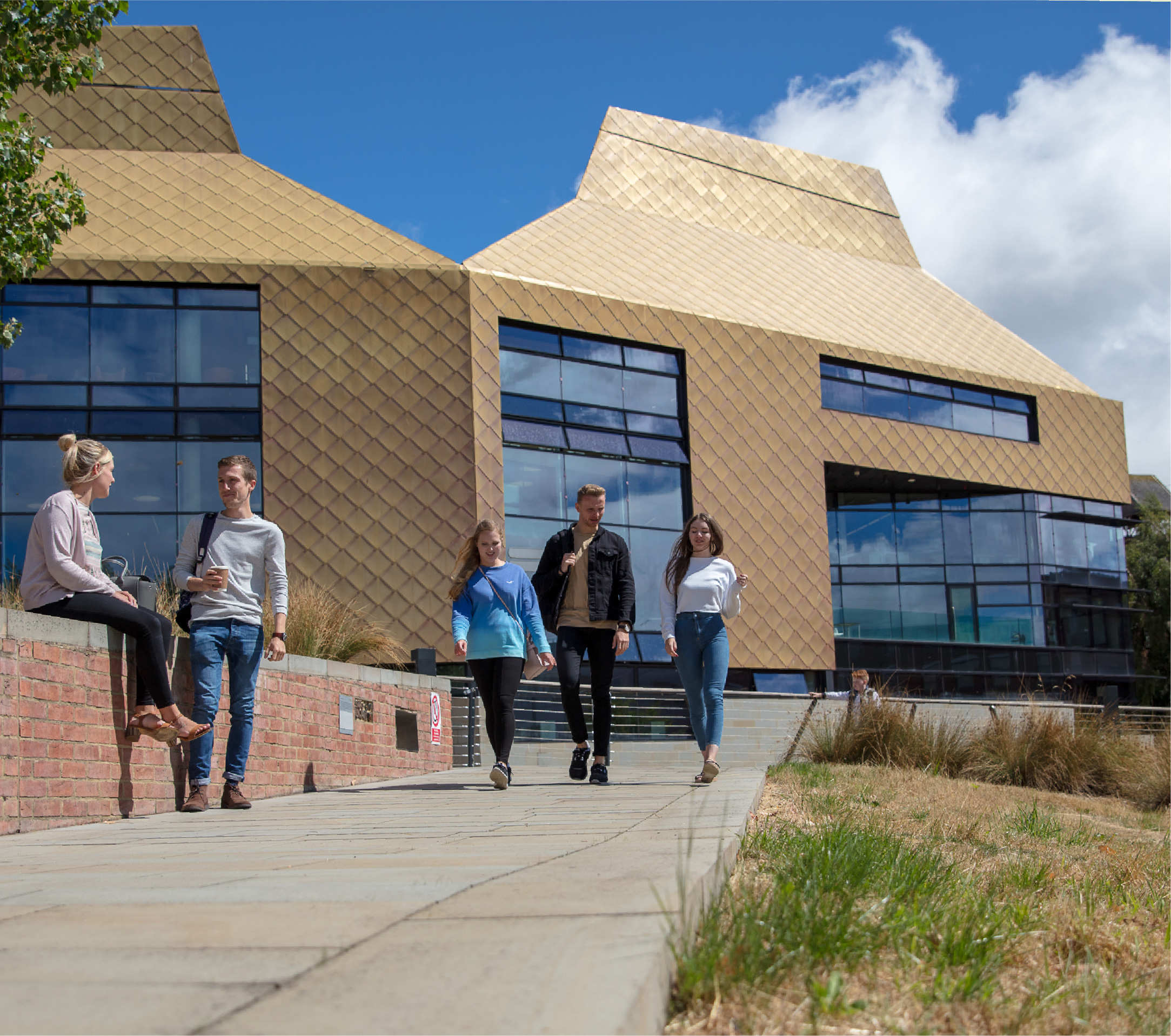 Students walking down a path with the Hive library behind them