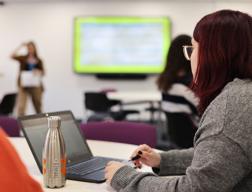 A girl sat in a seminar room, listening to a lecture