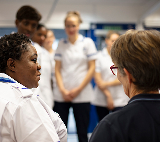 Healthcare students stood together and listening to a lecturer