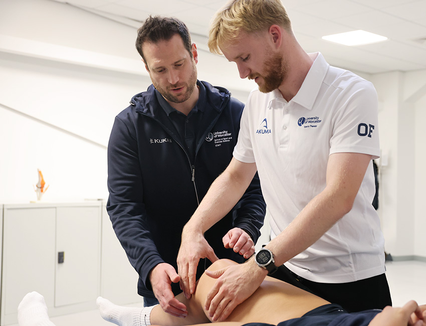 A lecturer helping a student to treat a patient's knee