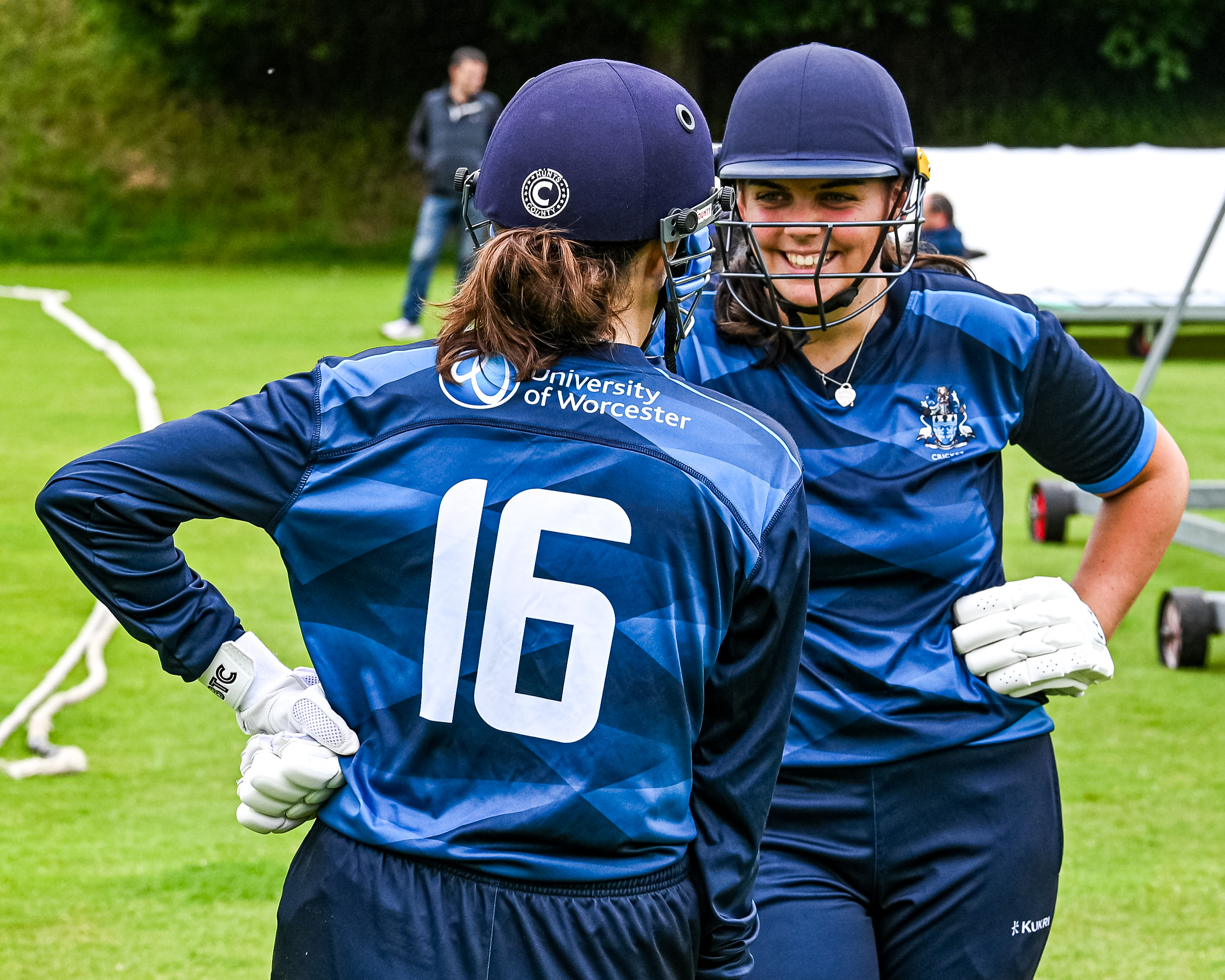 Two female cricket players in batting kit