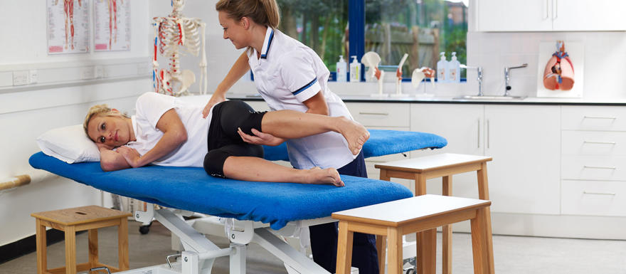 patient of a physio table stretching with physiotherapy student.