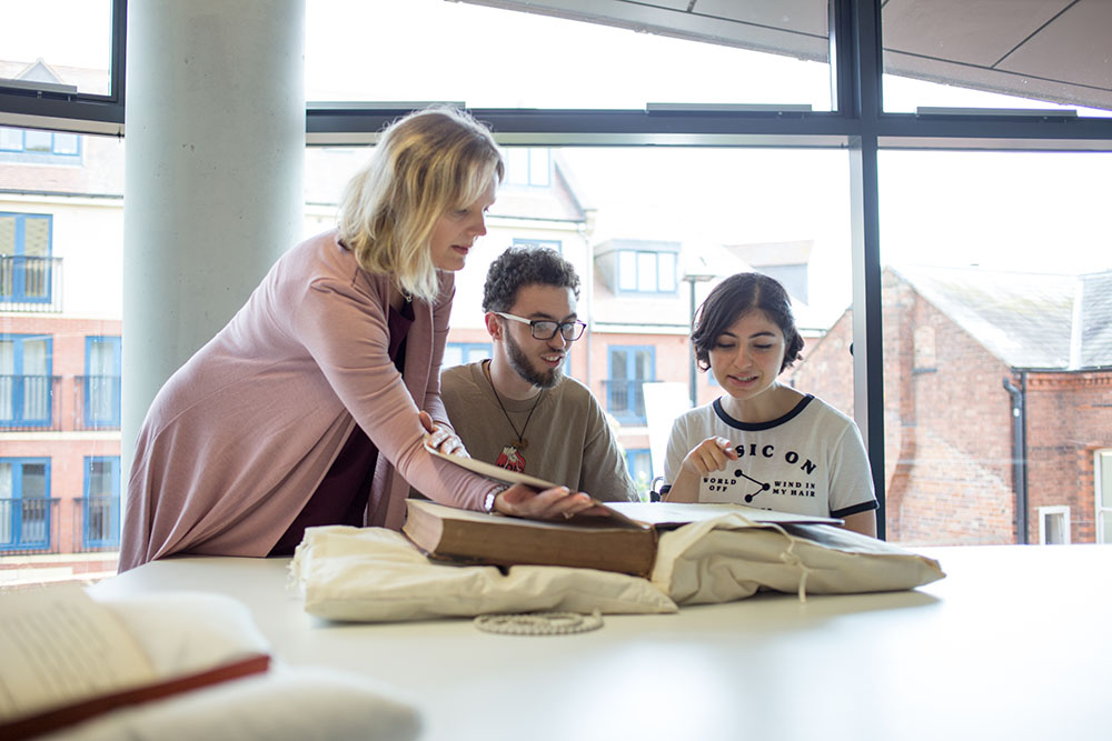 Three people looking at an old book