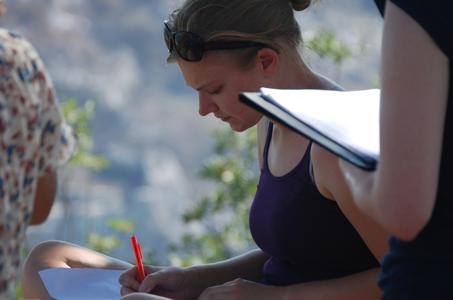 student writing in the outdoors with glasses on her head