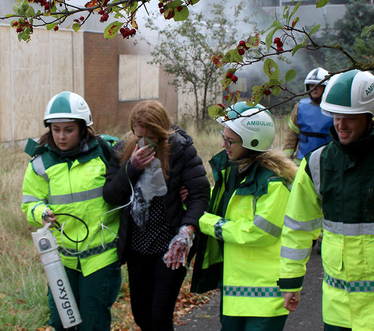 Student paramedics leading patient away from smoke during training day