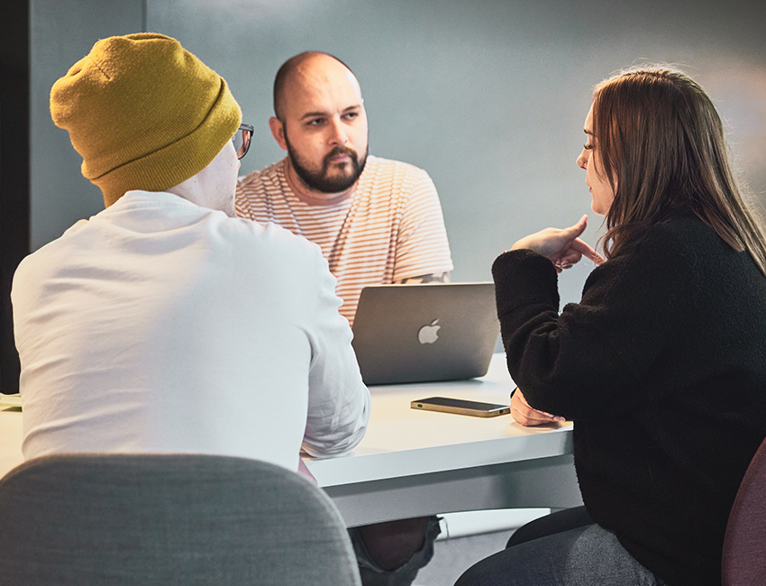 Three students gathered around a laptop