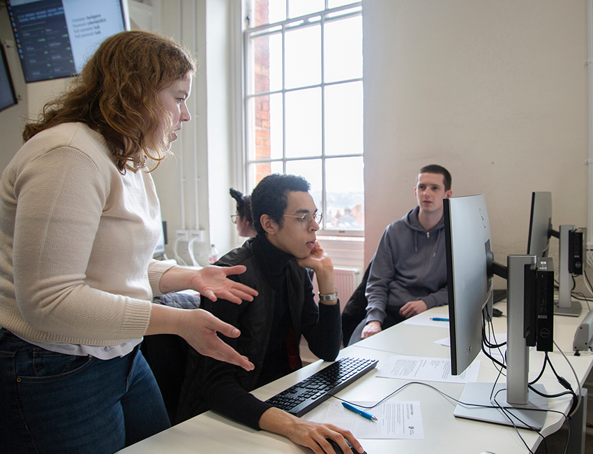 A lecturer supporting a student with a computer task