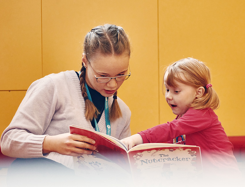 An Early Years student reading a book with a young child