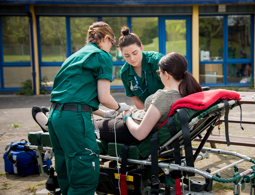 Two paramedic science students looking after person on a stretcher