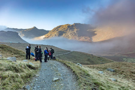 students on a road beside a misty valley