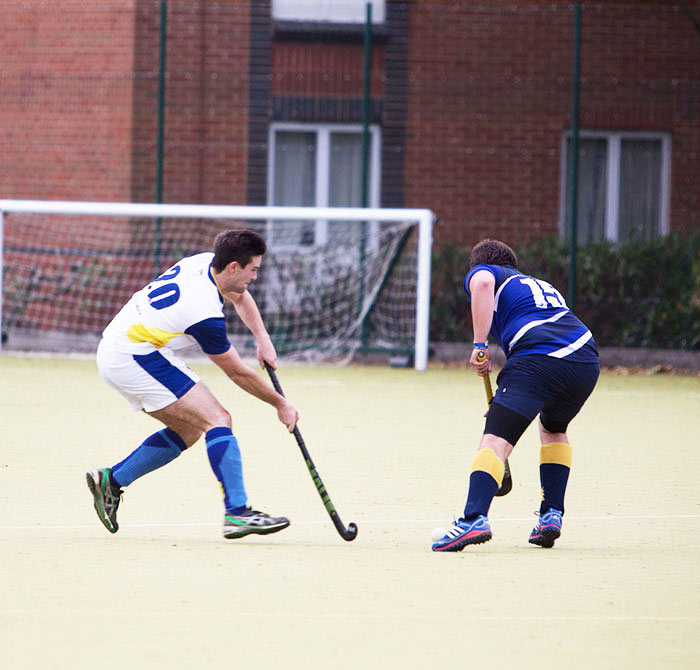 men playing hockey on an outside pitch