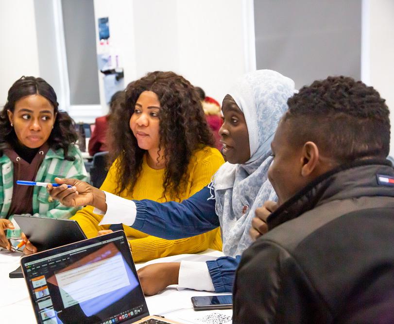 students around a table and one of them is pointing