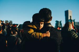 A child in the arms of their parent in a large crowd