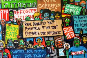 An illustration of a protest, with signs reading: "water for people, not for profit" and "refugees welcome", among many others